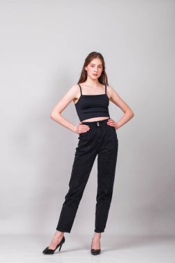 Gri arka planda izole edilmiş genç ve güzel bir esmer modelin vücut portresi.