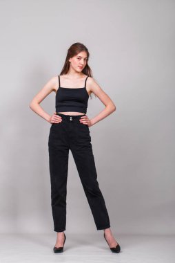 Gri arka planda izole edilmiş genç ve güzel bir esmer modelin vücut portresi.