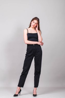 Gri arka planda izole edilmiş genç ve güzel bir esmer modelin vücut portresi.