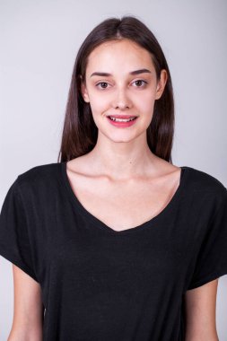 Gri arka planda soyutlanmış, güzel, mutlu, esmer bir kızın portresi.