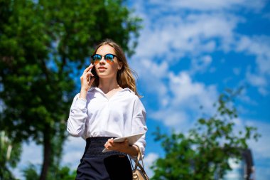 Beyaz bluzlu genç bir asistanın portresi. Sokaktan arıyor.