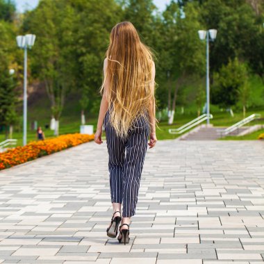 Yaz caddesinde poz veren güzel sarışın bir kadının vücut portresi.