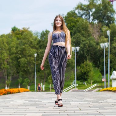 Yaz caddesinde poz veren güzel sarışın bir kadının vücut portresi.