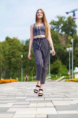 Yaz caddesinde poz veren güzel sarışın bir kadının vücut portresi.