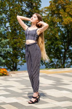Yaz caddesinde poz veren güzel sarışın bir kadının vücut portresi.