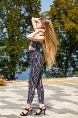 Yaz caddesinde poz veren güzel sarışın bir kadının vücut portresi.