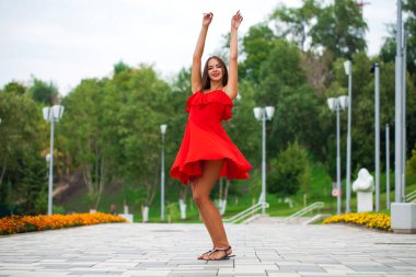 Tam büyümüş portre, kırmızı elbiseli güzel esmer kadın sokakta yürüyor, yaz seti açık.