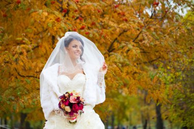 Sonbahar parkında gülümseyen güzel bir gelinin portresi.