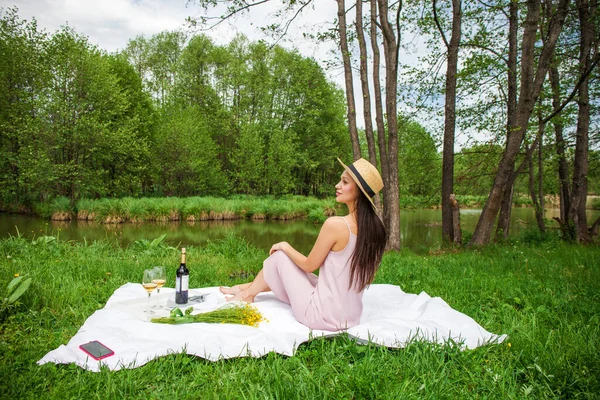 若い美しいブルネットの女性が夏の公園で芝生の上で休んでいる — ストック写真