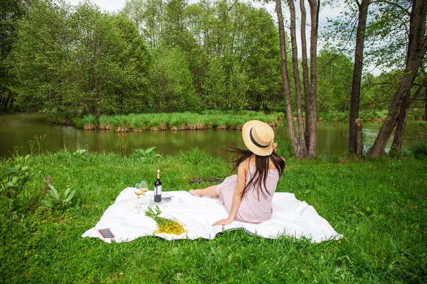 若い美しいブルネットの女性が夏の公園で芝生の上で休んでいる — ストック写真