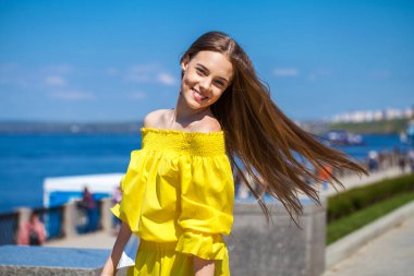 Sur boyunca yürüyen sarı elbiseli güzel bir tennager kızın yakın portresi. 