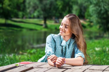 Bir yaz parkının arka planında genç bir kızın yakın plan portresi
