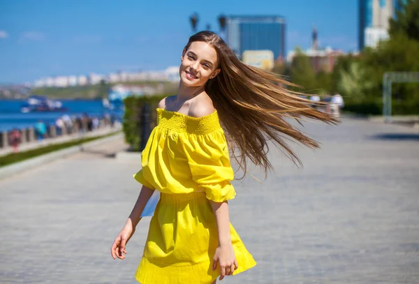 一个穿着黄色衣服的年轻漂亮的张灯结彩的少女沿着堤岸走着的特写 — 图库照片
