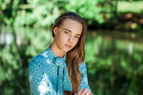 一个身穿绿松石衣服的年轻漂亮少女在夏园池塘的背景下摆姿势的画像 — 图库照片