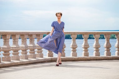 Mavi elbiseli güzel, esmer bir kadının tam boy portresi.