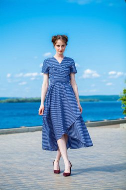 Mavi elbiseli güzel, esmer bir kadının tam boy portresi.