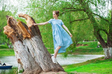 Bir yaz parkında, turkuaz bir elbise içindeki güzel bir kadının portresi.