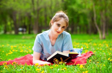 Bir yaz parkında kitap okuyan genç ve güzel bir kız.