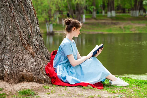 若いです美しいですブルネット女の子読書A本でA夏公園 — ストック写真