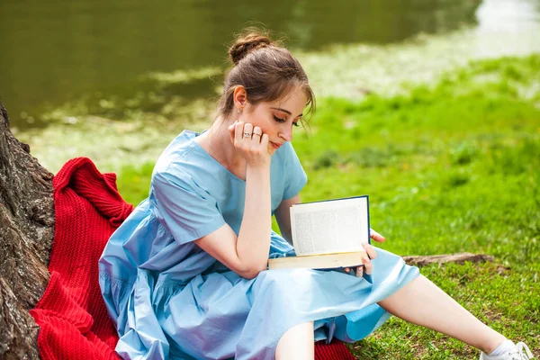 若いです美しいですブルネット女の子読書A本でA夏公園 — ストック写真