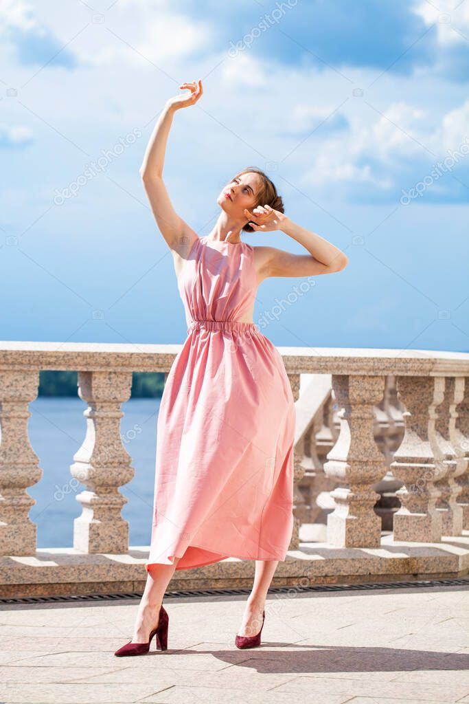 Full length portrait of young beautiful brunette woman in pink dress