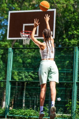 Genç güzel esmer kız basketbol sahasında poz veriyor.