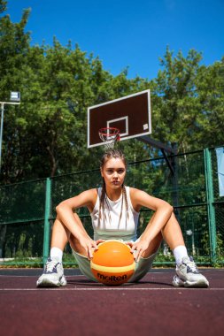 Genç güzel esmer kız basketbol sahasında poz veriyor.