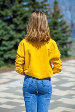 Arkadan bakıldığında, mavi kot pantolonlu sarışın manken, yaz parkı açık havada.