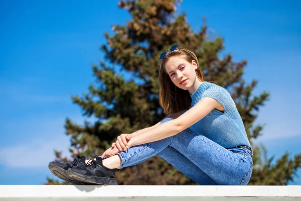 Açık hava yaz parkında, kot pantolonlu güzel sarışın bir kızın portresi. 