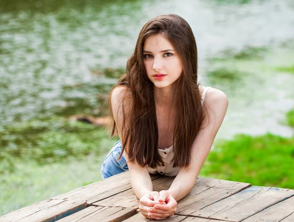 一个年轻貌美的姑娘在夏日公园的池塘后面摆姿势的画像 — 图库照片