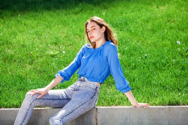 Mavi bluzlu ve gri kotlu güzel esmer kız, açık hava yaz parkı. 