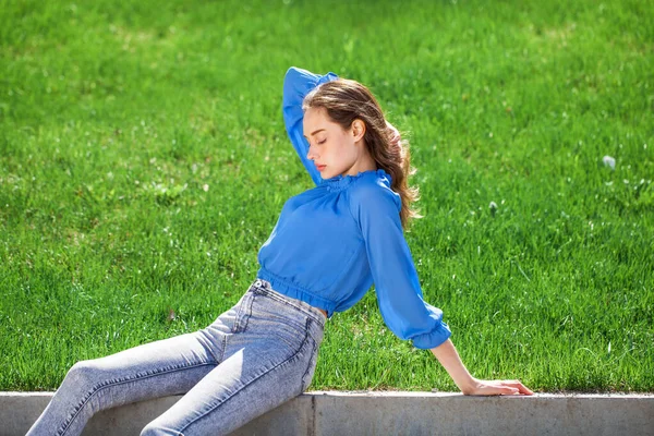 穿着蓝色衬衫和灰色牛仔裤的年轻漂亮的黑发女孩 夏天公园外 — 图库照片