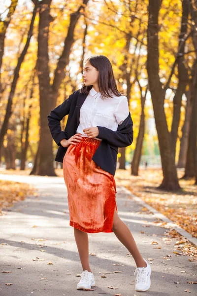 一个穿着橙色裙子在秋天公园散步的年轻黑发女子的全身像 — 图库照片