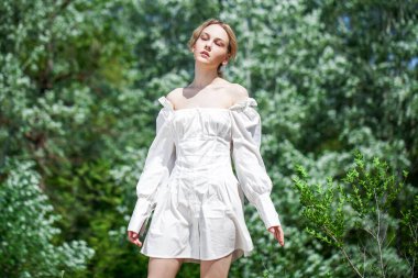 Beyaz elbiseli, uzun kollu ve arkası kesilmiş güzel bir kız.