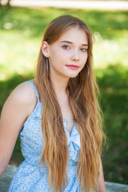 Bir yaz parkının arka planında genç bir kızın yakın plan portresi