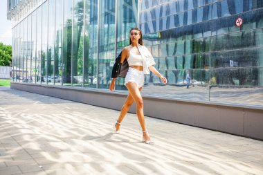 Yaz caddesinde yürüyen güzel esmer bir kızın vücut portresi.