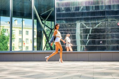 Yaz caddesinde yürüyen güzel esmer bir kızın vücut portresi.