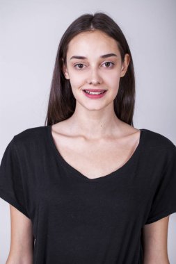 Gri arka planda soyutlanmış, güzel, mutlu, esmer bir kızın portresi.