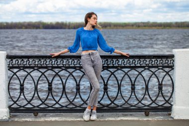 Mavi bluzlu ve gri kotlu güzel kız.