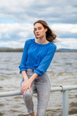 Mavi bluzlu ve gri kotlu güzel esmer kız, açık hava yaz parkı. 