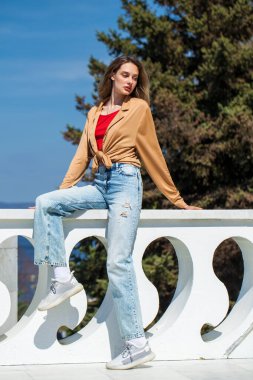 Uzun kollu ve mavi kotlu bej bluzlu genç bir kızın tam boy portresi.