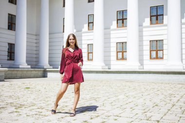 Burgundy elbiseli güzel bir kızın uzun bir portresi. 