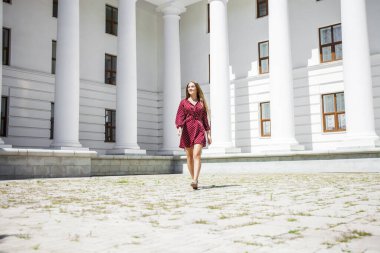 Burgundy elbiseli güzel bir kızın uzun bir portresi. 