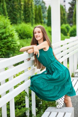 Yeşil elbiseli genç bir sarışının vücut portresi.