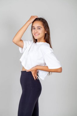 Gri arka planda soyutlanmış, güzel, mutlu, esmer bir kadının portresi.