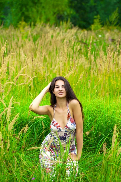 Ung smuk pige sidder på grønt græs - Stock-foto