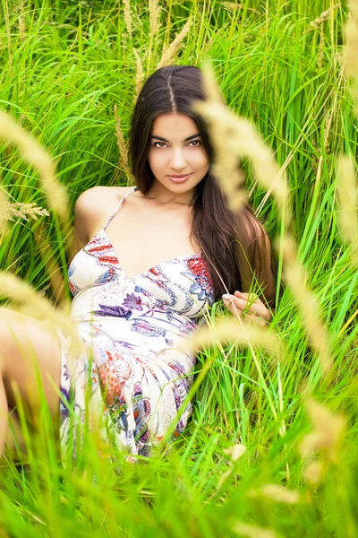 Jovem mulher descansando e dia deitado na grama verde — Fotografia de Stock