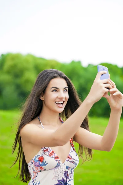 Menina bonita feliz fotografado em um telefone celular em um pa verão — Fotografia de Stock