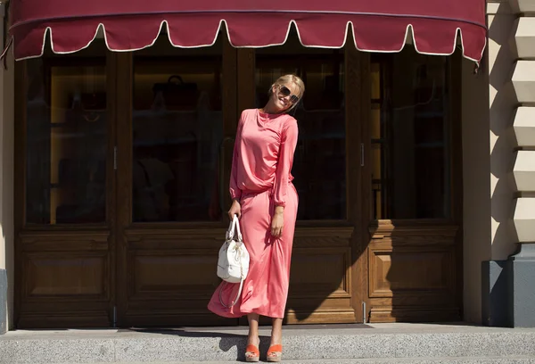 Krásná mladá žena v růžových šatech v obchodě — Stock fotografie
