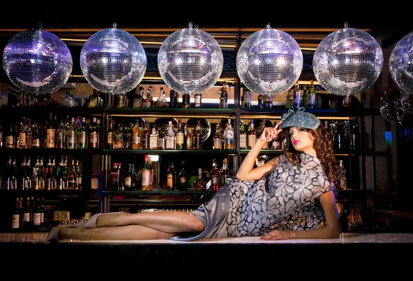 Sexy young woman lying on the bar at a night disco club — Stock Photo, Image